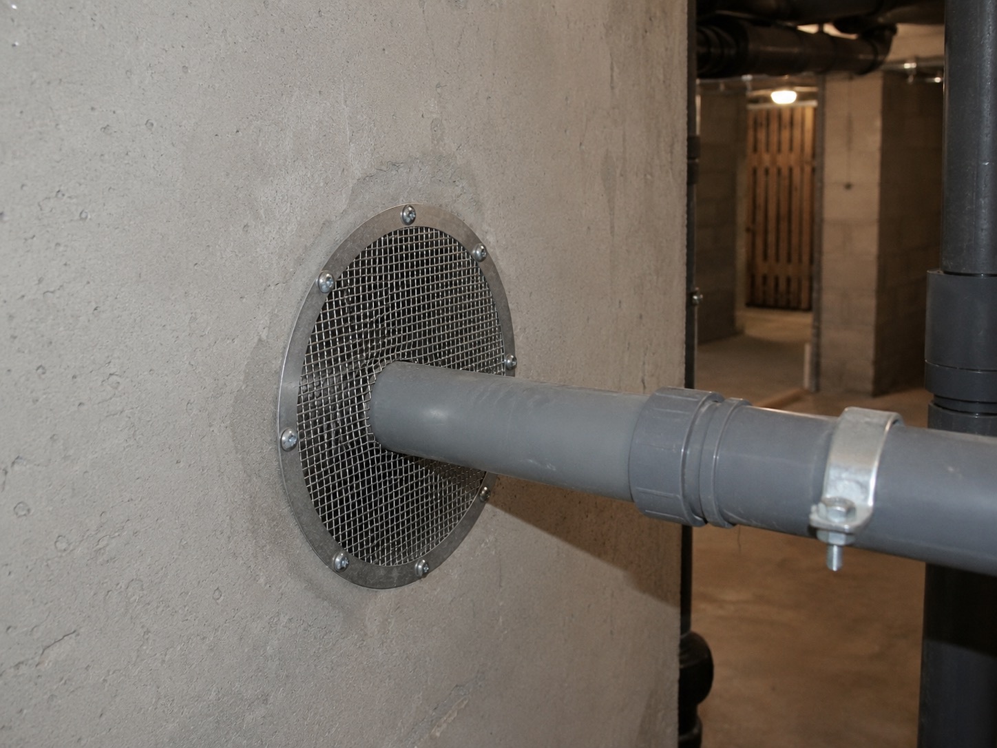 Grille anti-rongeurs posée sur un passage de canalisation en sous-sol
